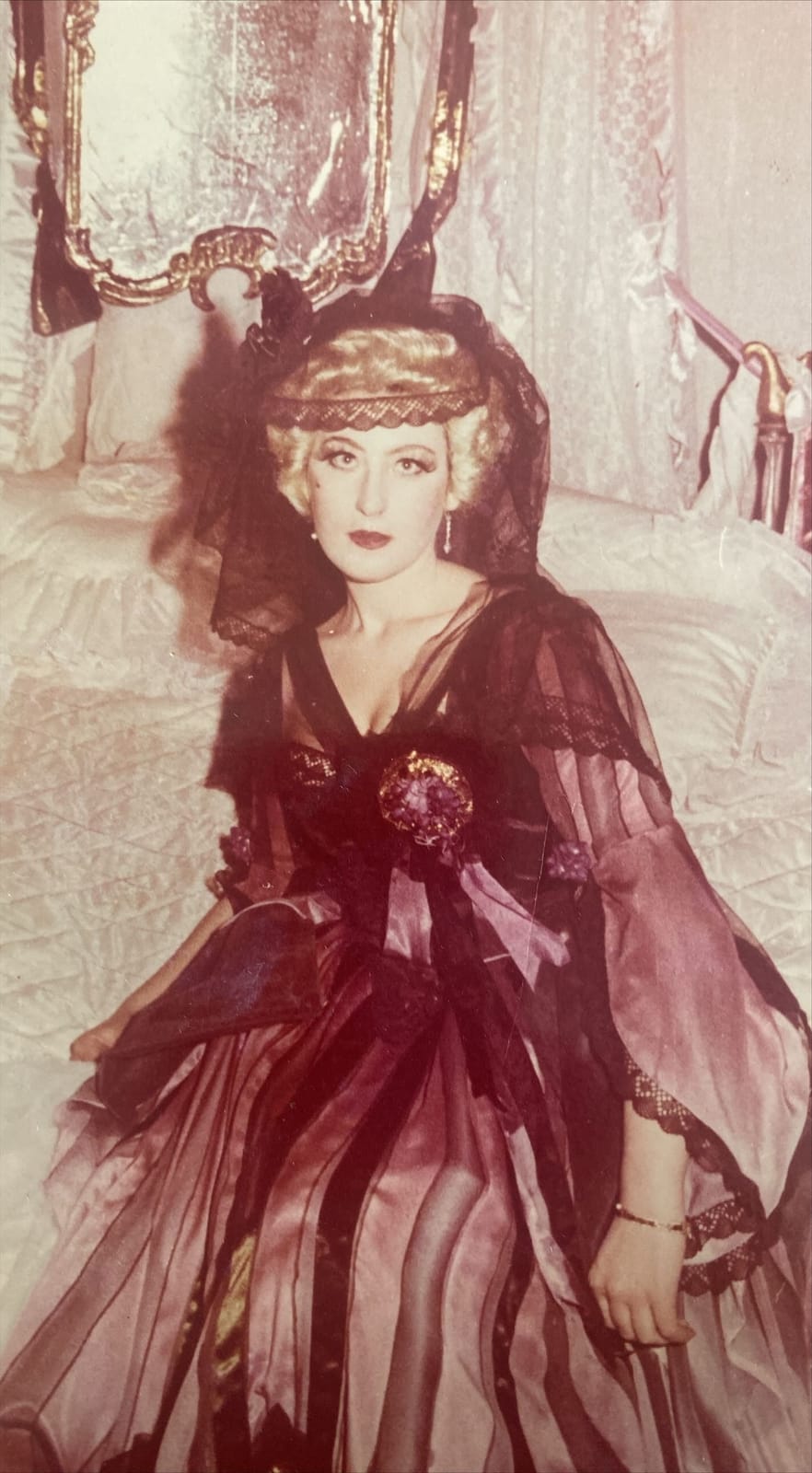 Archival role photograph: boudoir scene in a striped gown with a black lace veil.