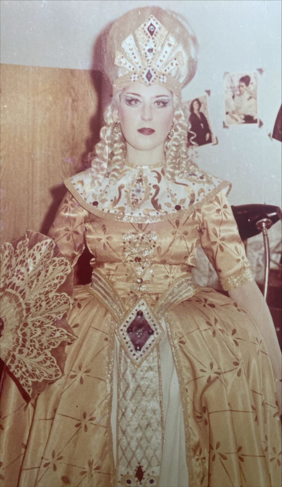 Archival role photograph: golden gown and tall jewelled headdress with braids.