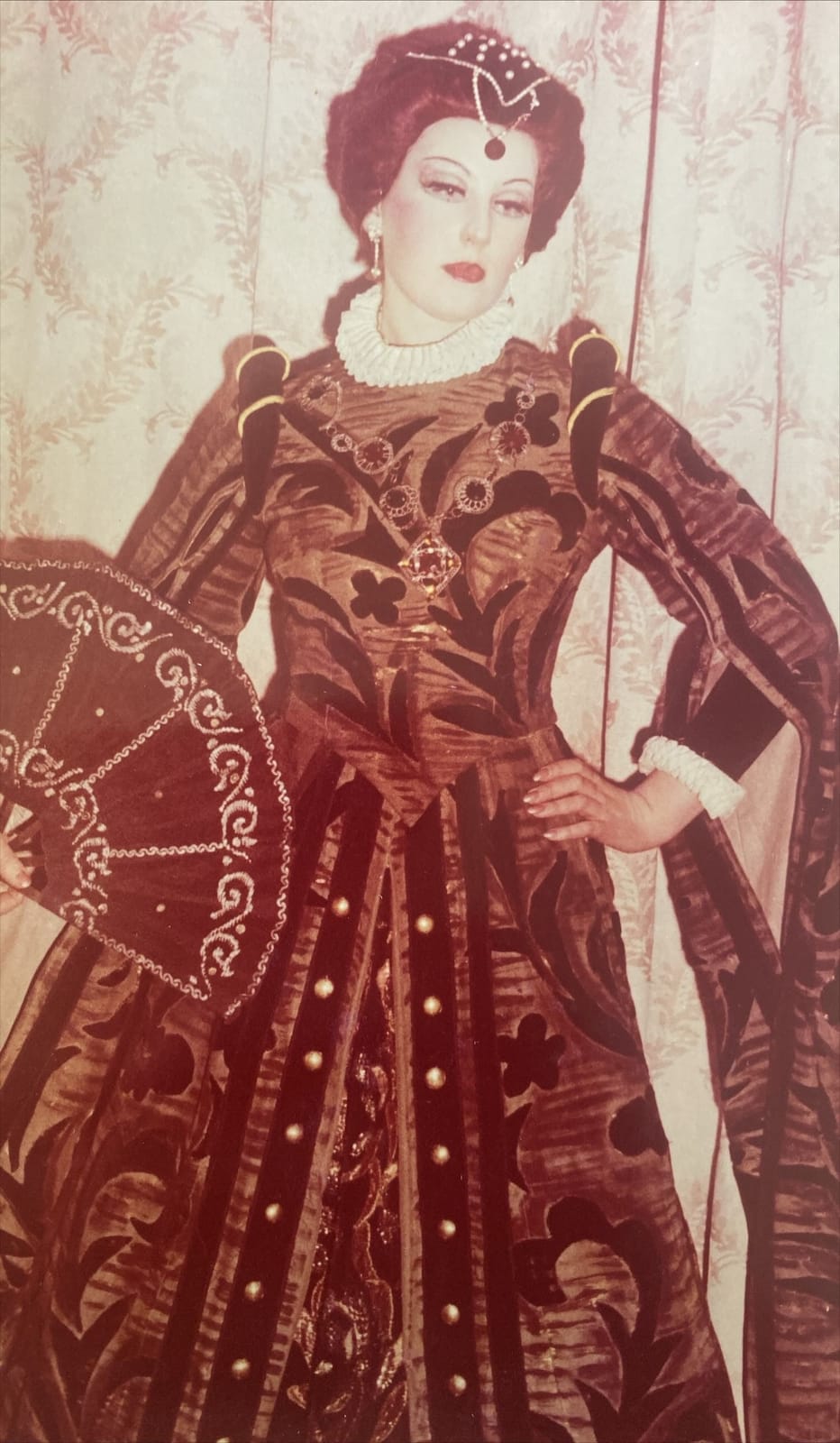 Archival role photograph: royal court costume with a fan and pearl headdress.