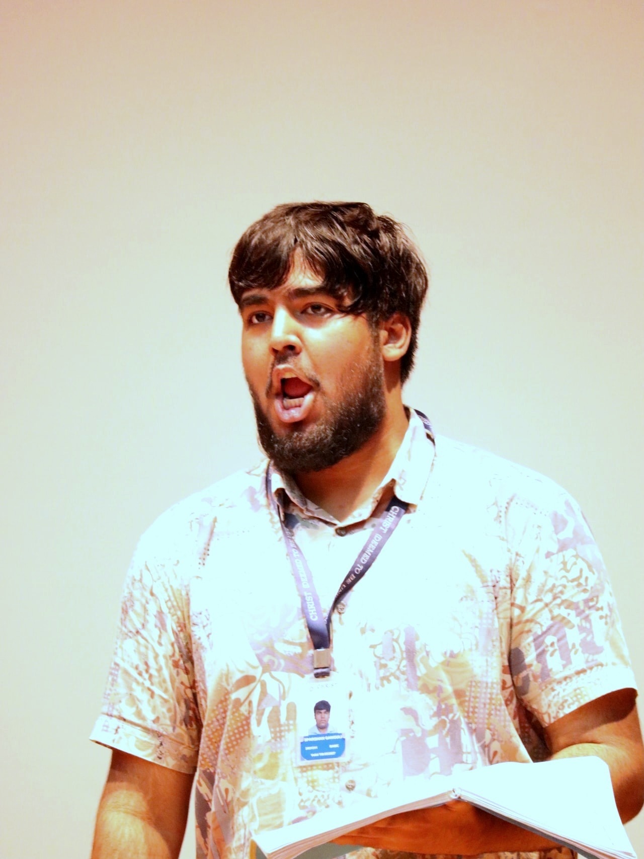A singer in rehearsal, score in hand, mid-phrase.