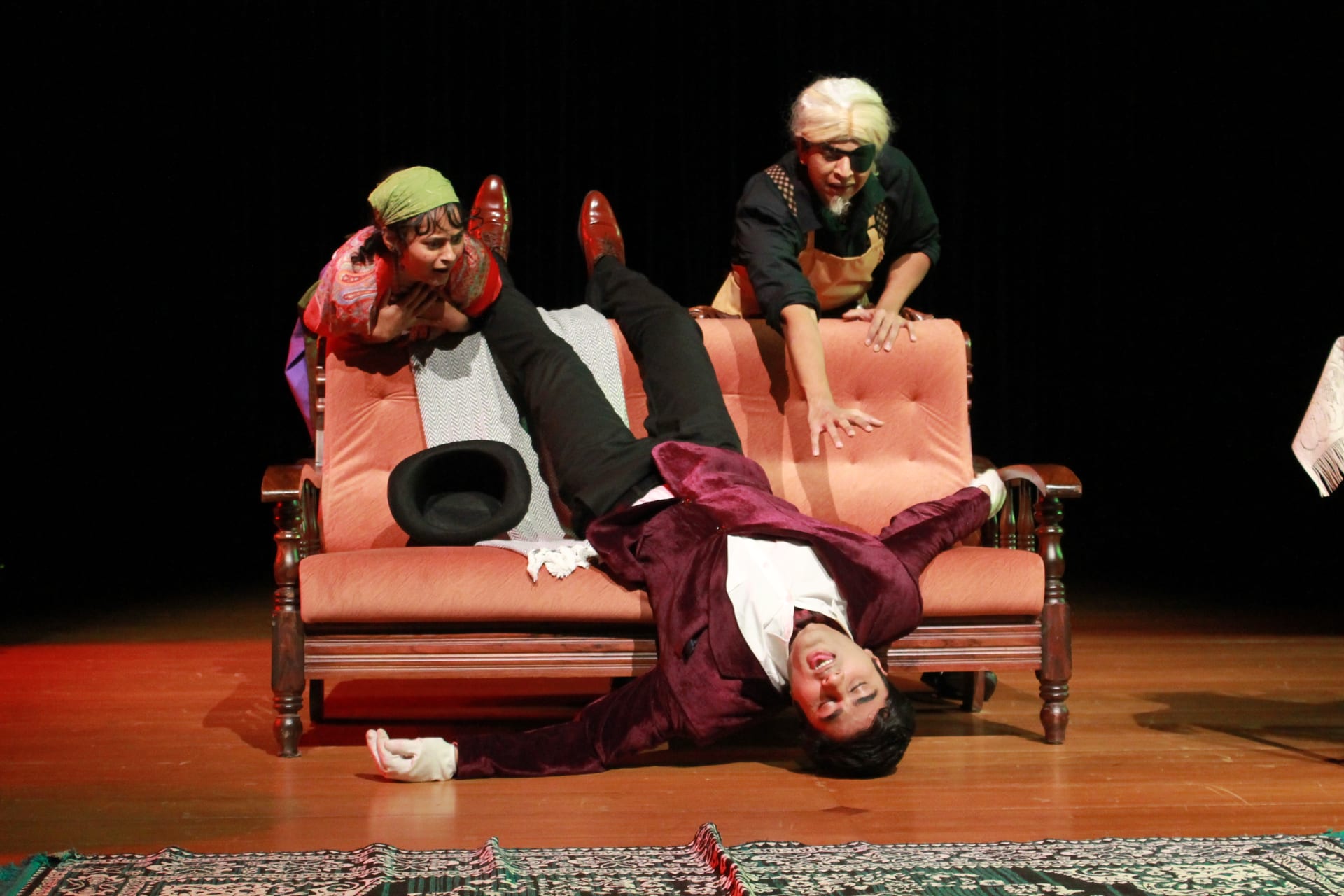Scene from The Proposal: a man collapses on the sofa as two women lean over him