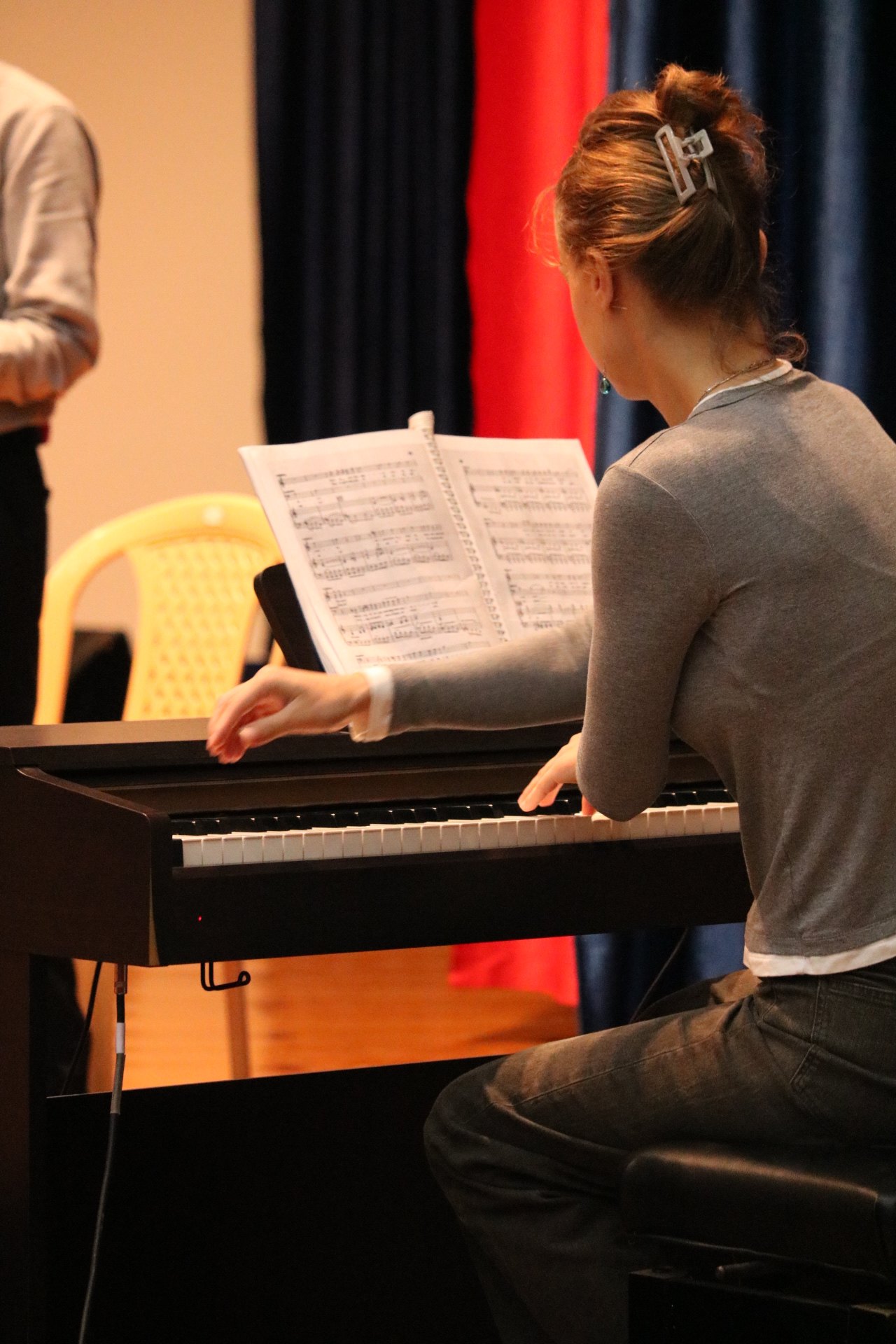 The répétiteur at the piano, score open, red curtain behind — a rehearsal of Gianni Schicchi.