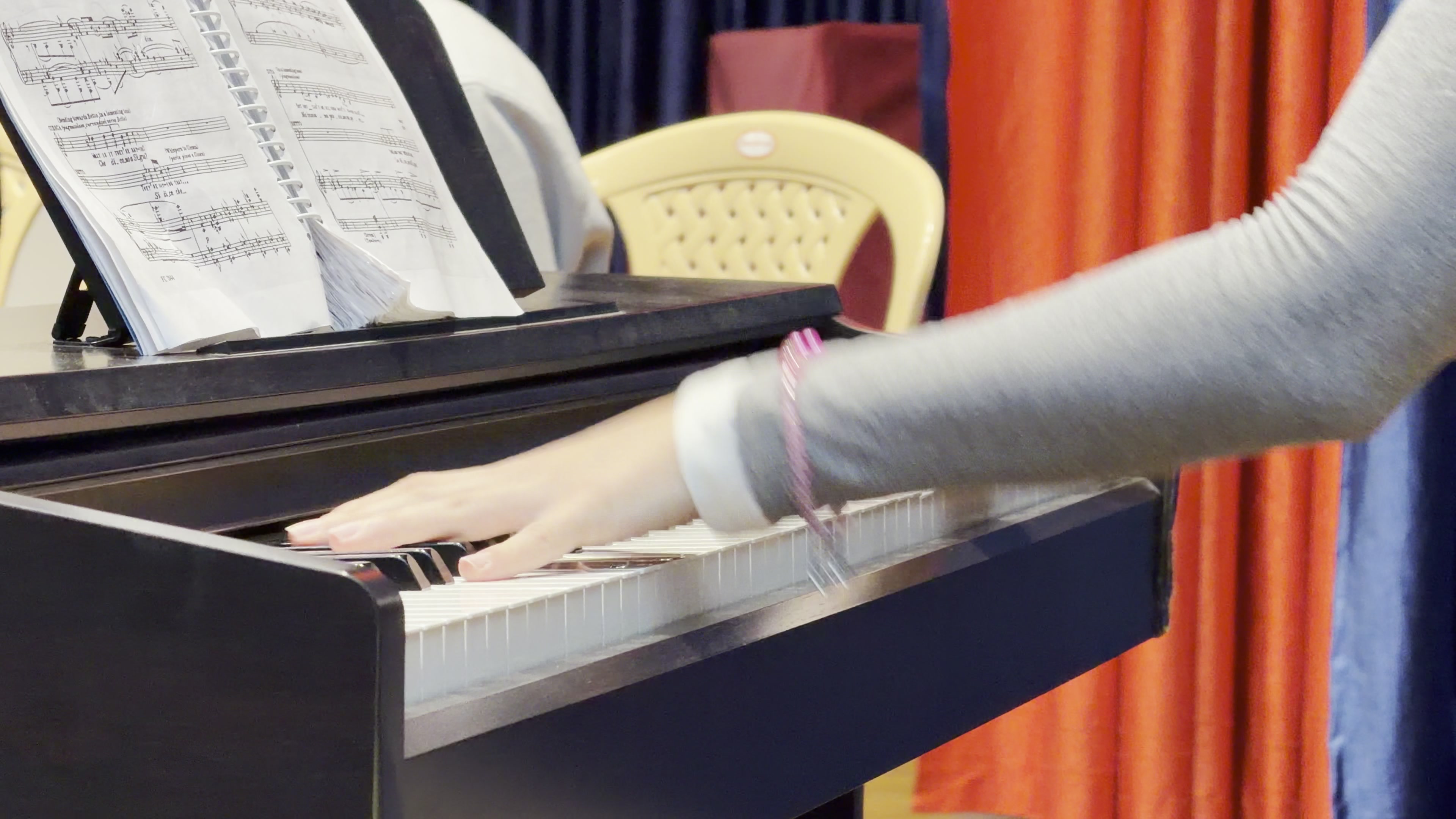 Close-up of the répétiteur's hands on the piano keys, the open score above them.